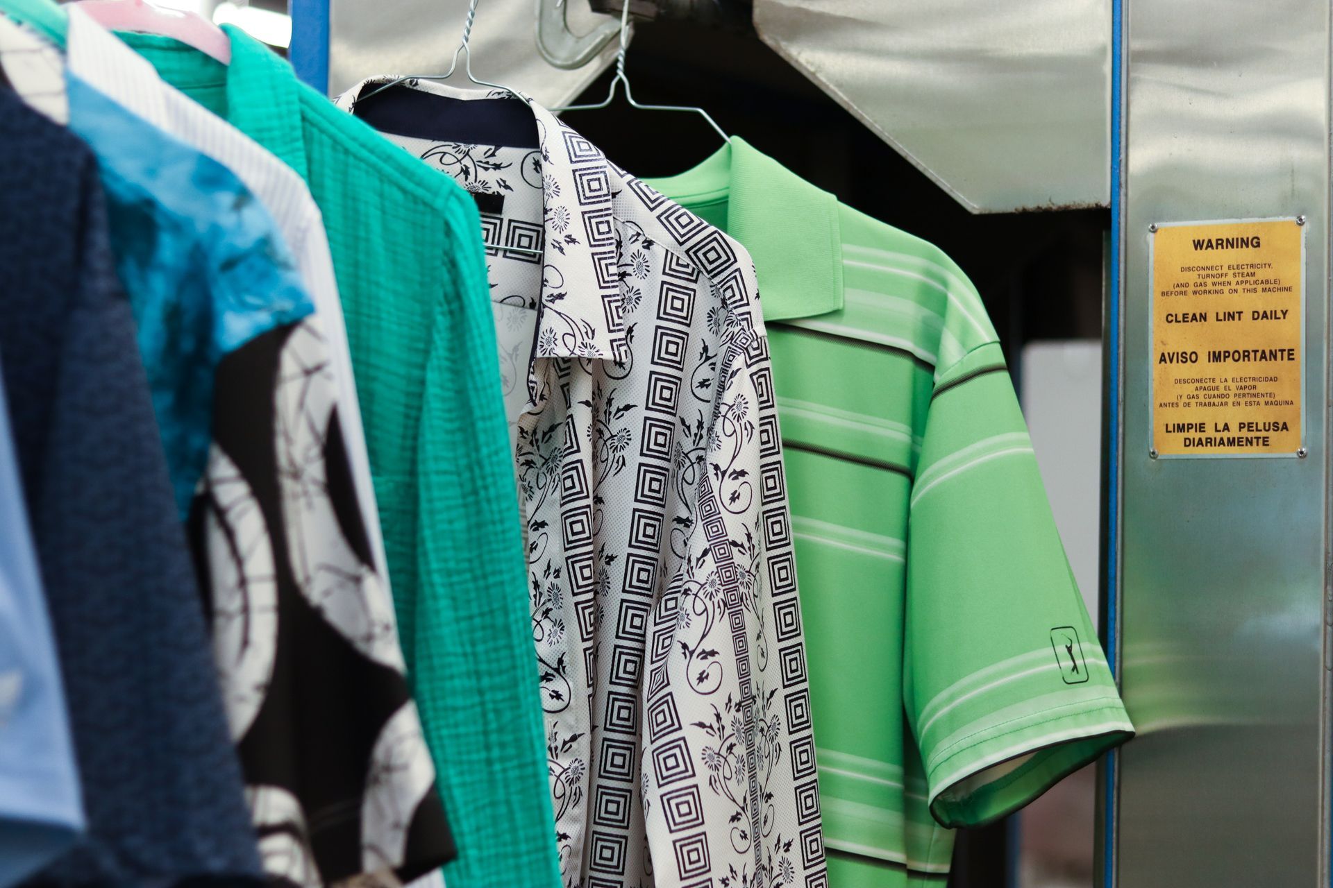 Clothes hanging on a rack: Blue, green, and patterned shirts.