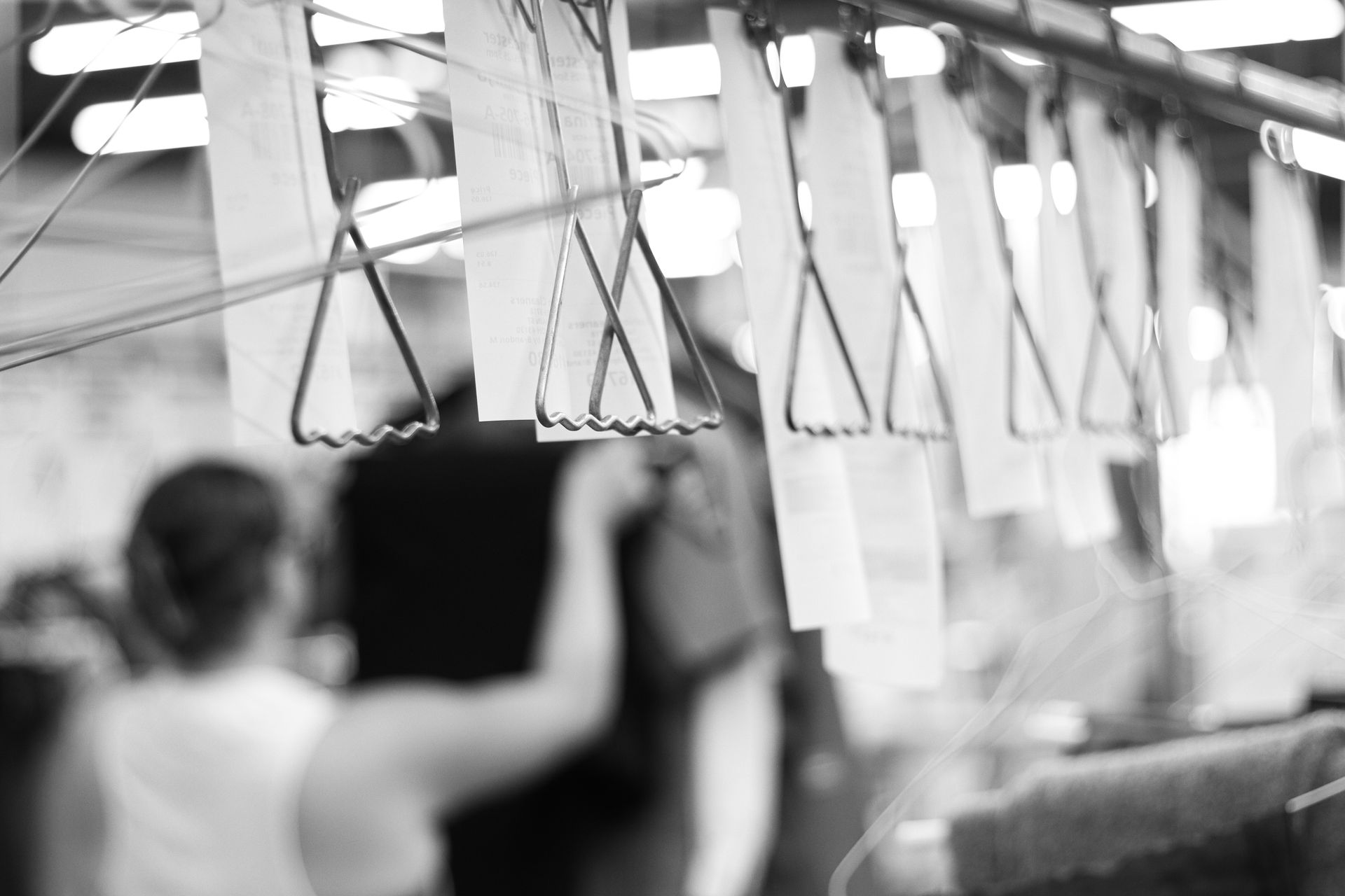 Clothing racks with hangers, blurred figures in the background.