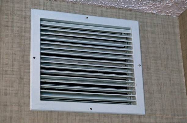 White square air vent on a textured wall, with horizontal slats and four visible screws.