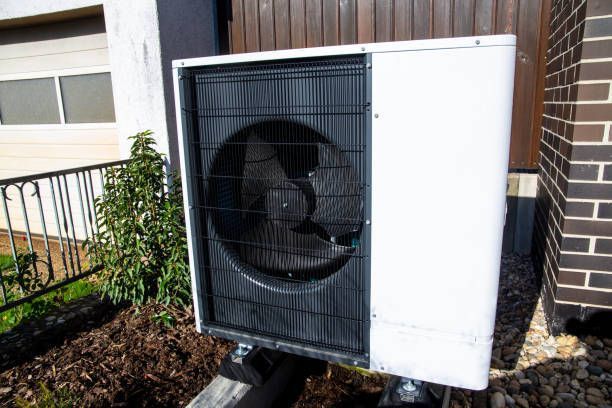 A person using gauges to check an air conditioner unit. Blue and orange gauges are visible.