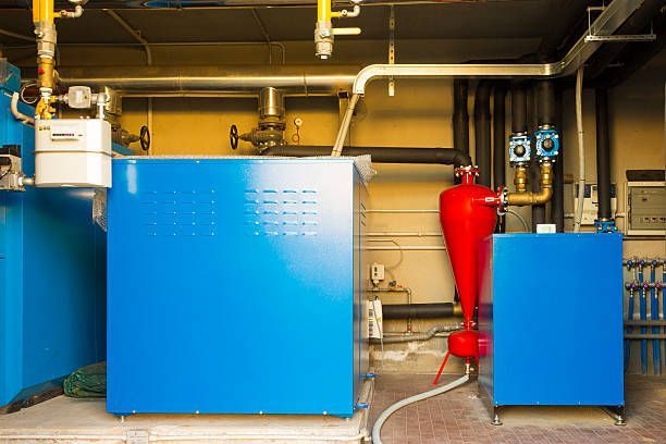 Blue industrial machinery with gas lines and a red filter in a utility room.