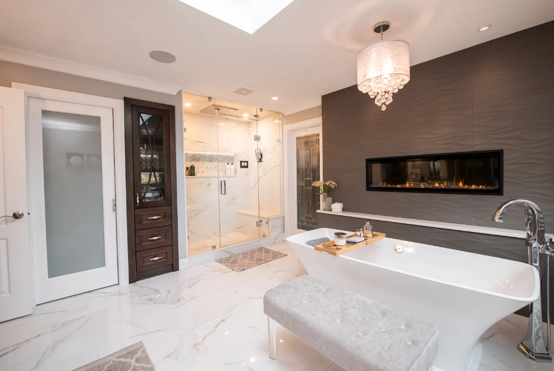 Modern white bathroom with freestanding tub, glass shower, dark accent wall, and pendant light