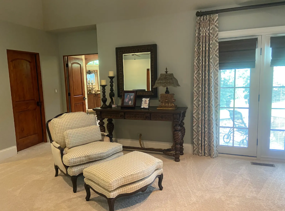 Bright living room with chaise lounge, console table, mirror, and French doors with curtains.