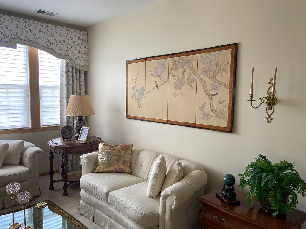 Elegant living room with cream sofa, side table, wall art, and window with patterned curtains