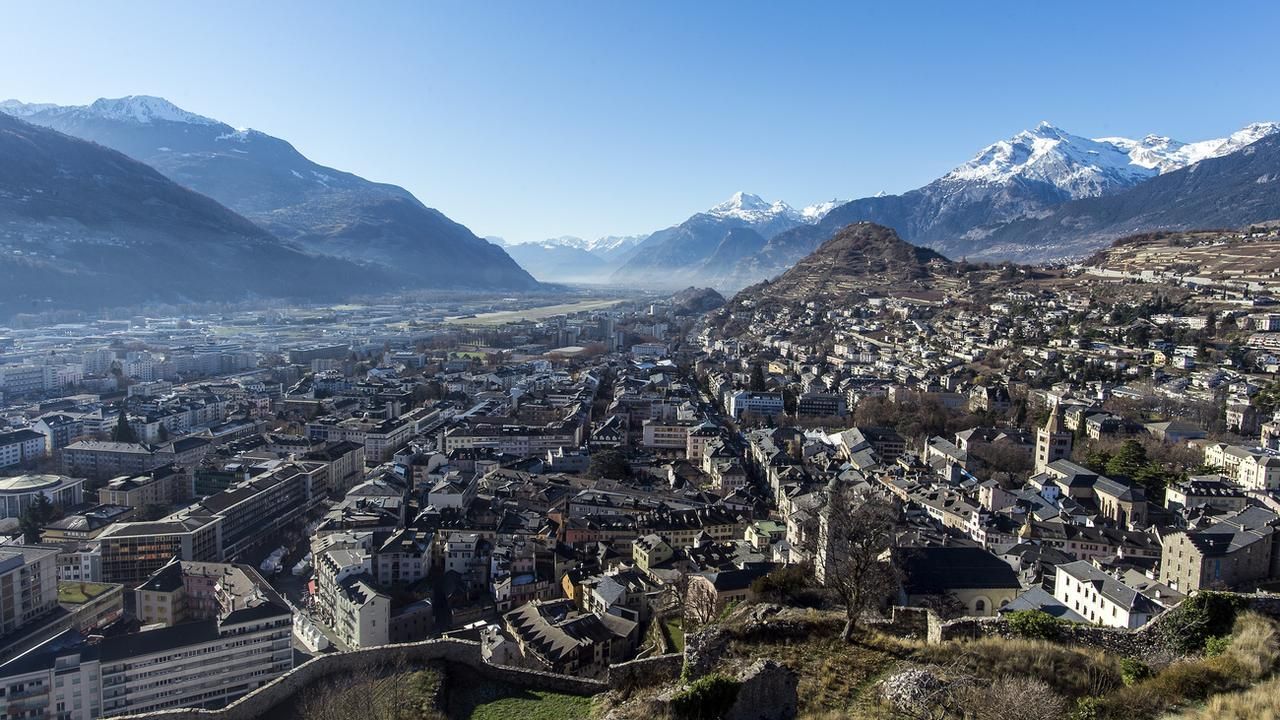 Vue panoramique d'une ville de vallée avec des montagnes à l'horizon sous un ciel dégagé