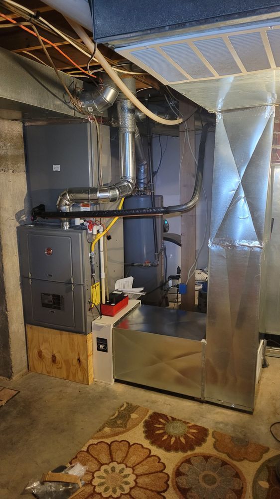 Basement HVAC furnace and ductwork beside a water heater, with insulated metal ventilation panels.