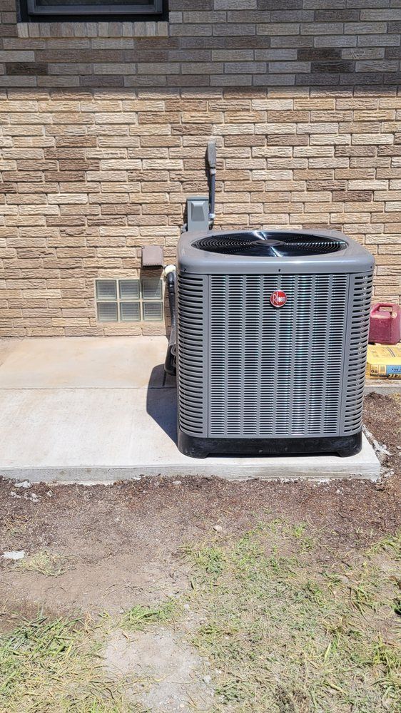 Outdoor air conditioner unit beside a brick house wall on a concrete pad