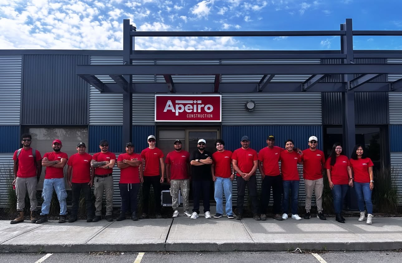 Group of people in red shirts and hats in front of a building with a sign that says 