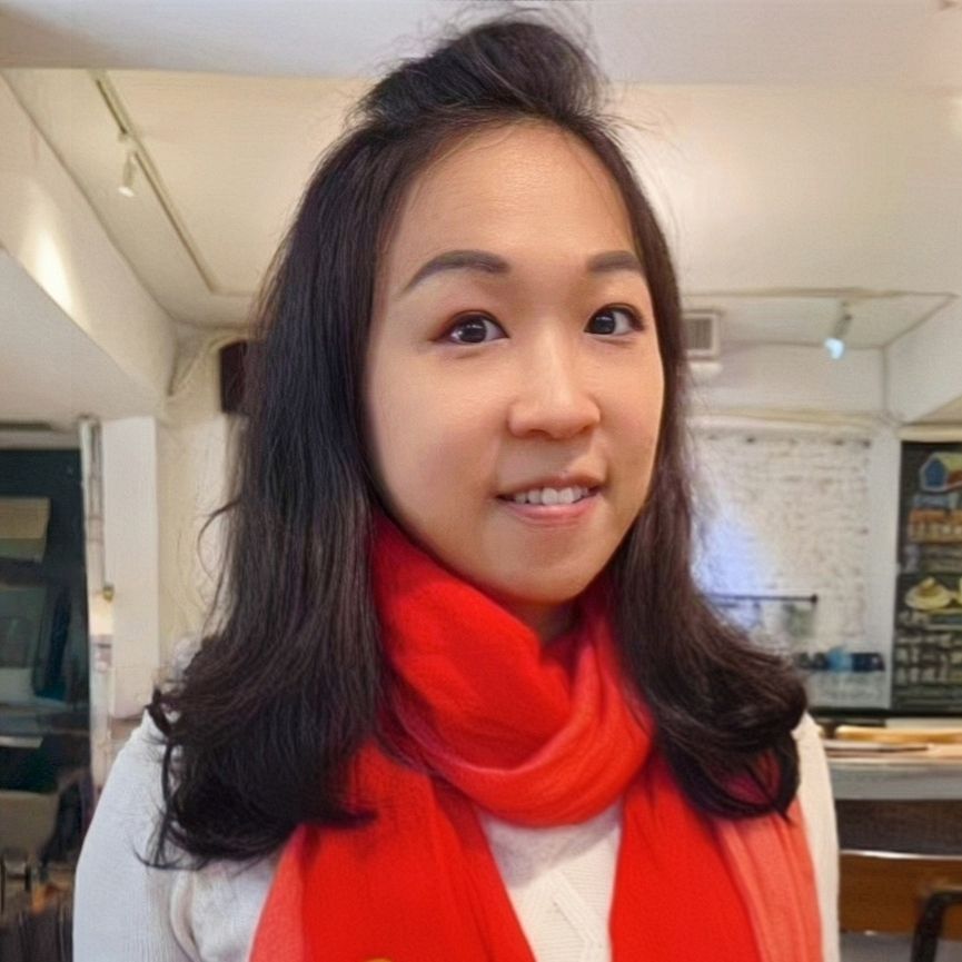 深色頭髮、戴著紅色圍巾、微笑的女子。室內,中性背景。