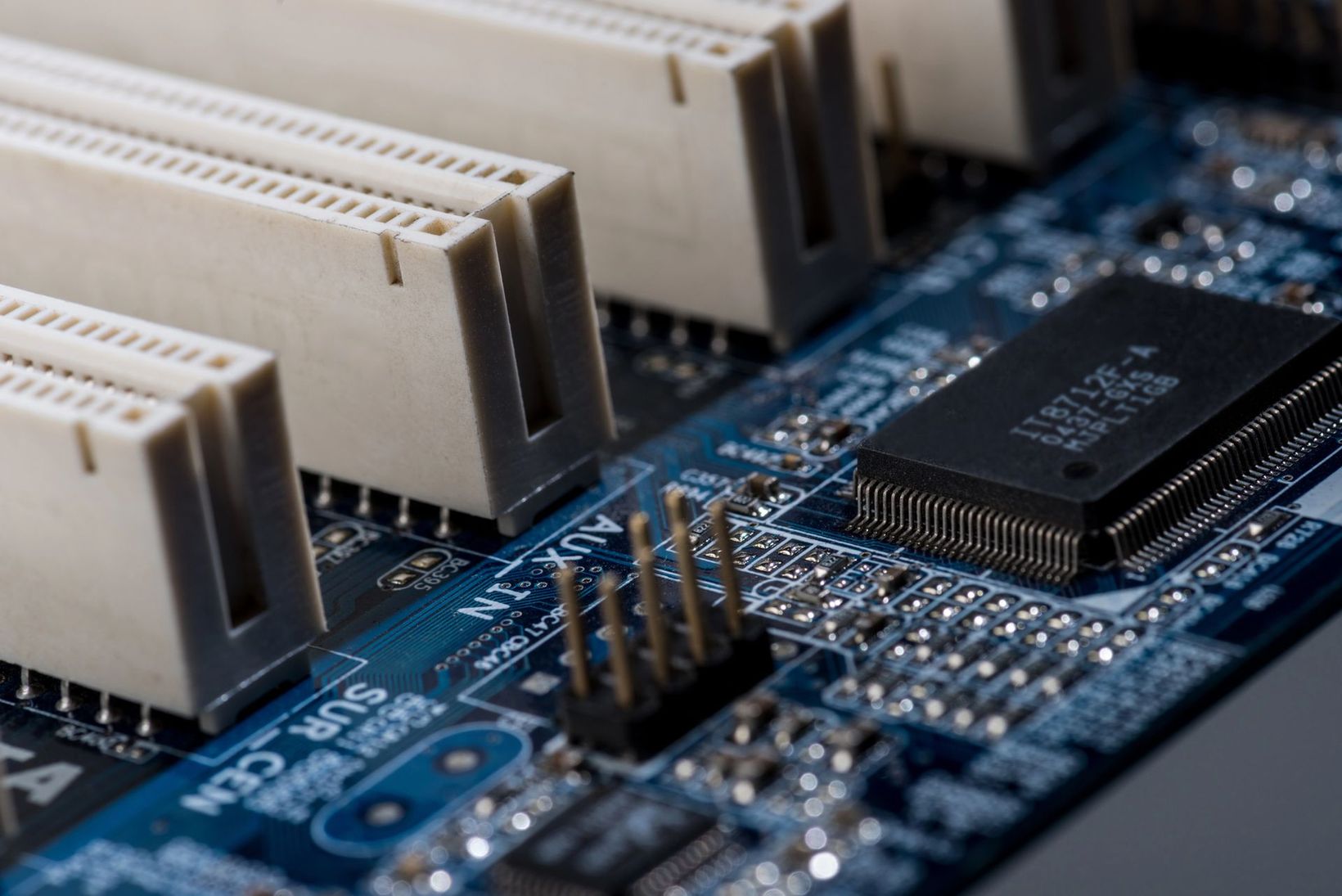 Primo piano di un circuito stampato blu con connettori bianchi e un microchip nero