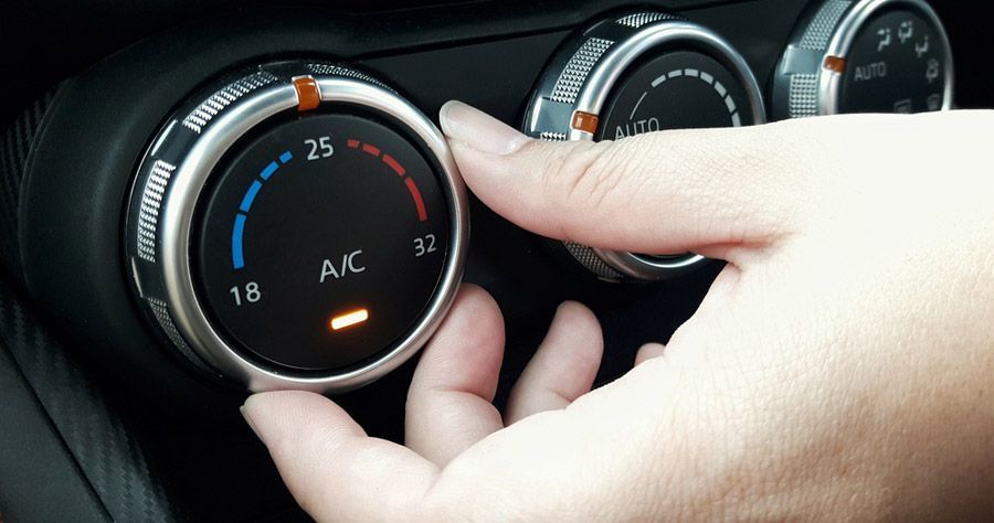 Hand turning the temperature dial in a car, showing blue and red temperature settings.