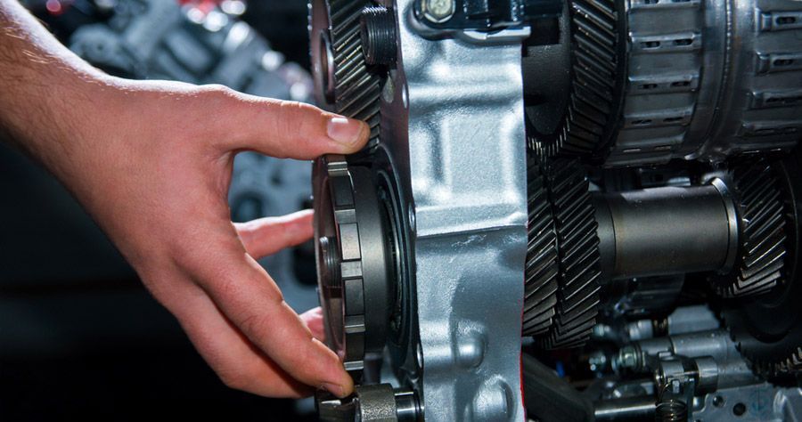 Hand inspecting gears inside an engine component.
