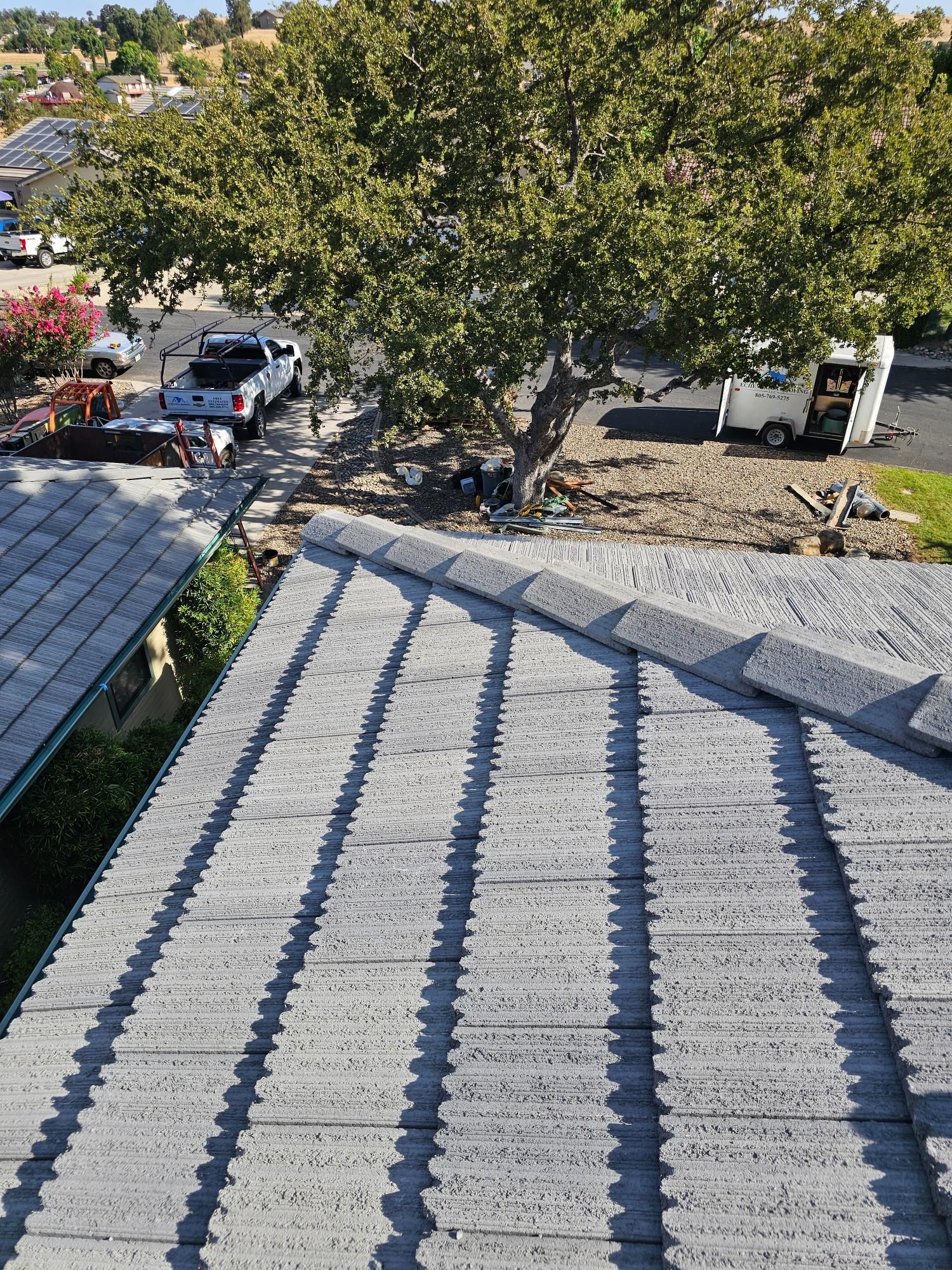 Solar panel roof with tree shadows beside a street and parked cars