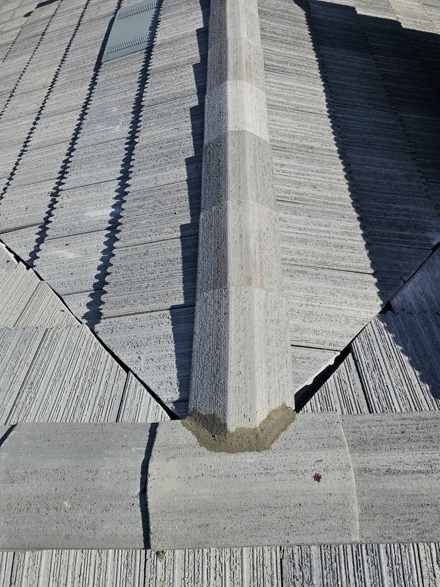 Close-up of a shingled roof valley with a light-colored ridge vent and gray asphalt shingles