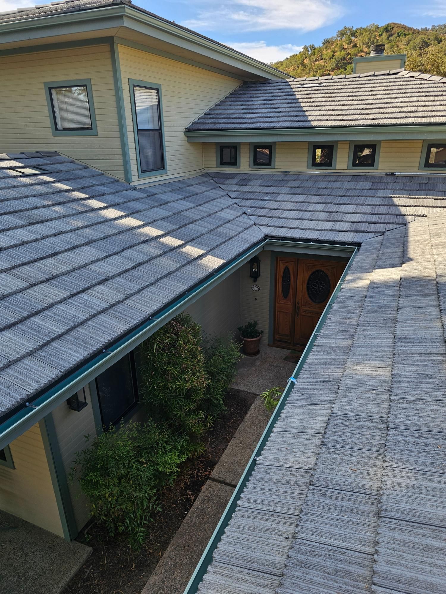 Courtyard view of a house with gray tiled roofs and a wooden front door, seen from above