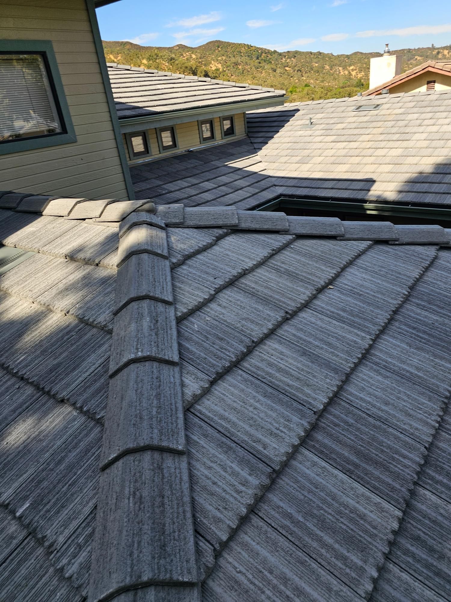 Solar-panel-covered shingle roof on a house, viewed from above with mountains in the background