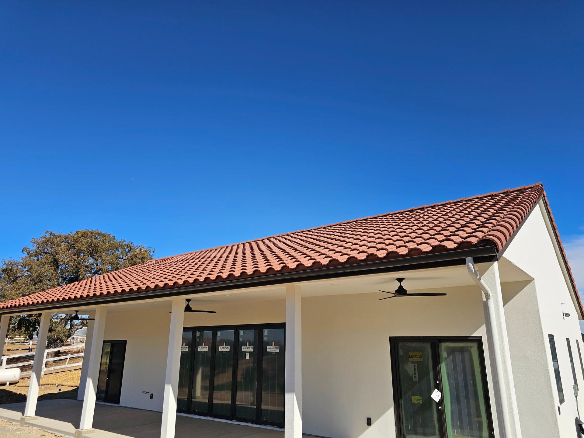 Modern single-story white house with a red tile roof under a clear blue sky