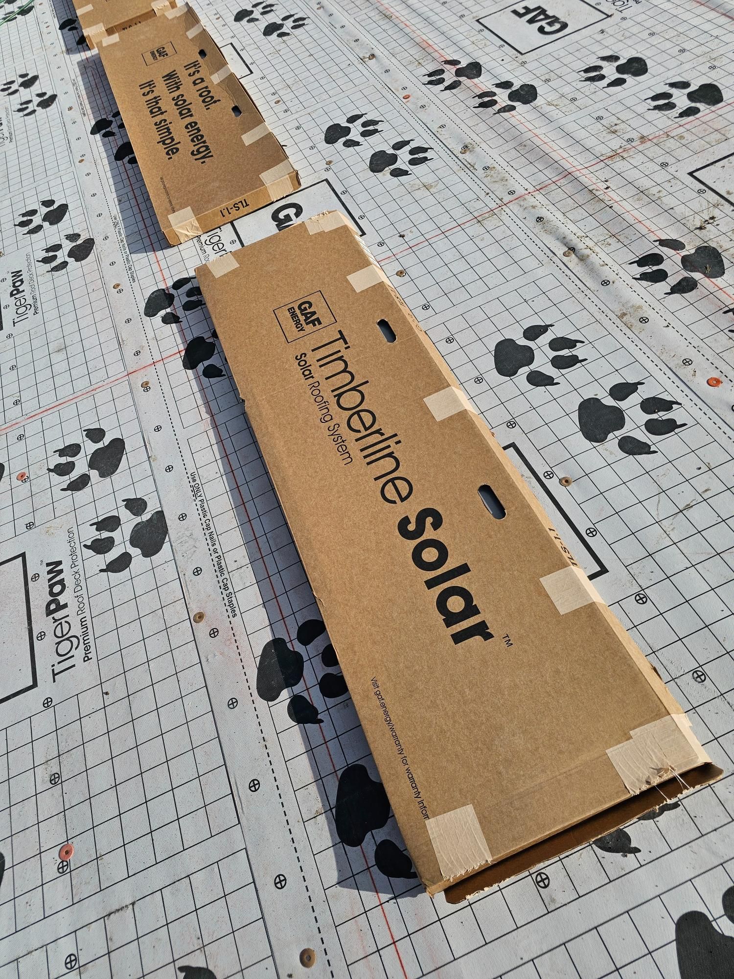 Cardboard shipping boxes on patterned packaging material, one labeled “happin solar.”