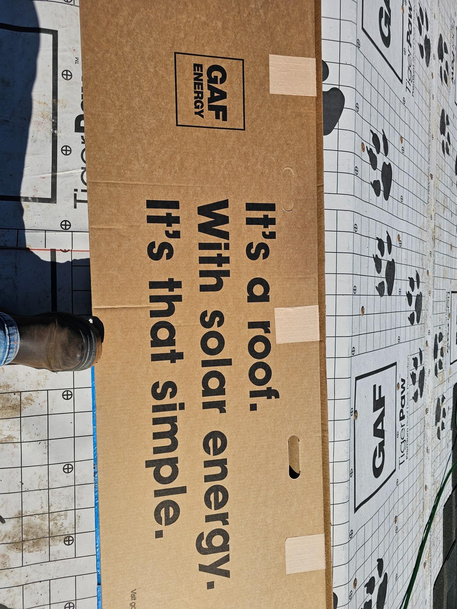 Cardboard sign reading “It’s a roof. With solar energy. It’s that simple.” on a rooftop.