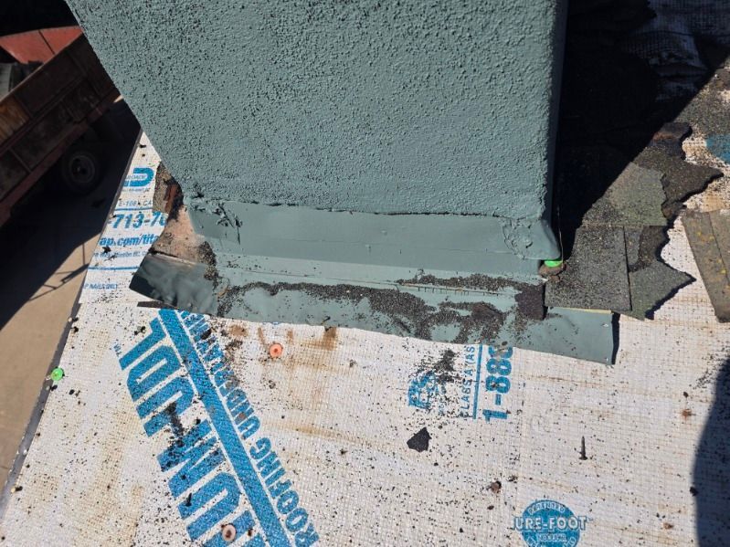Close-up of a gray concrete column base on waterproofing membrane, showing fresh sealant and debris.