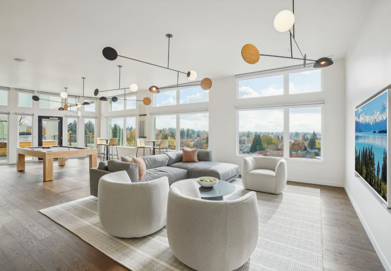 Bright modern living room with round white chairs, large windows, and ocean views.