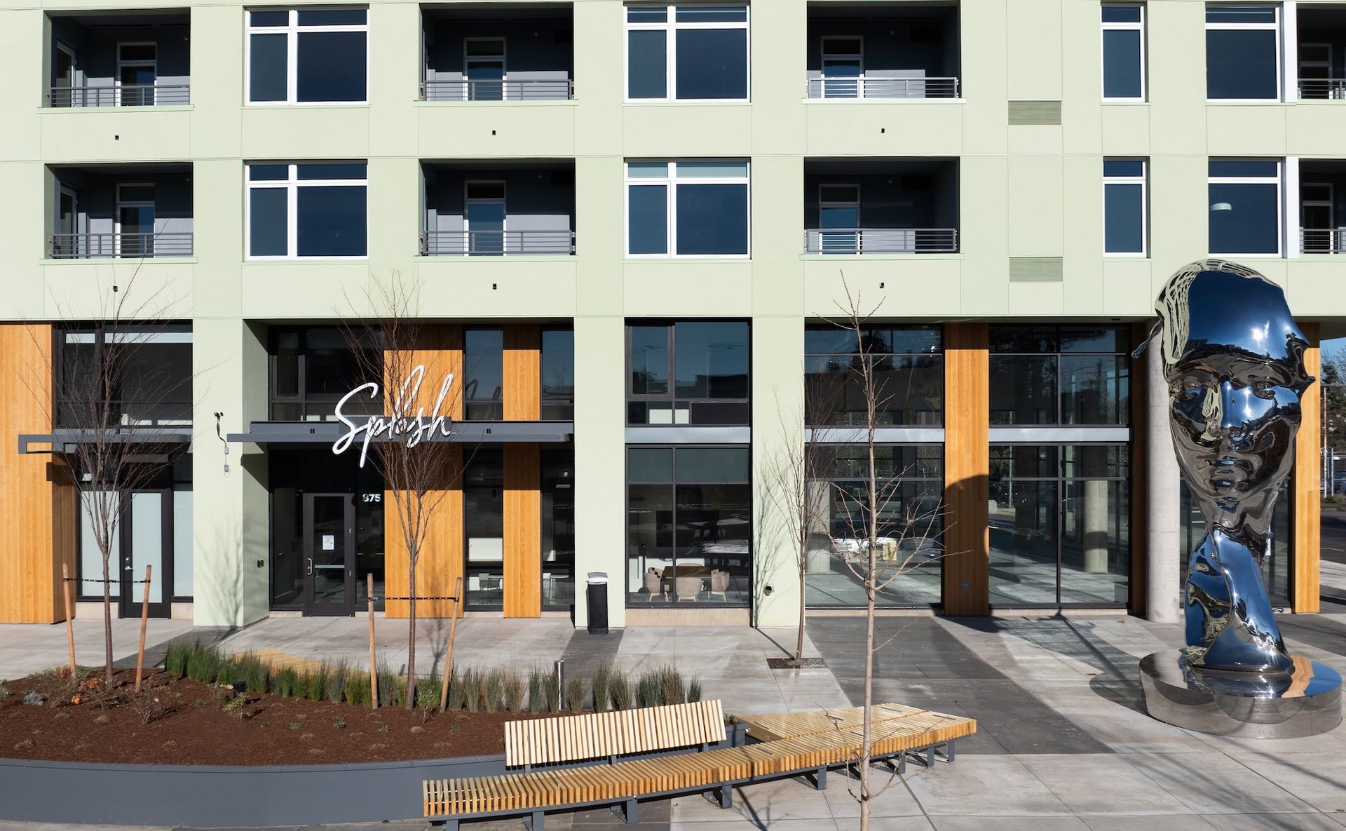 Modern apartment building entrance with orange accents and a large blue sculpture