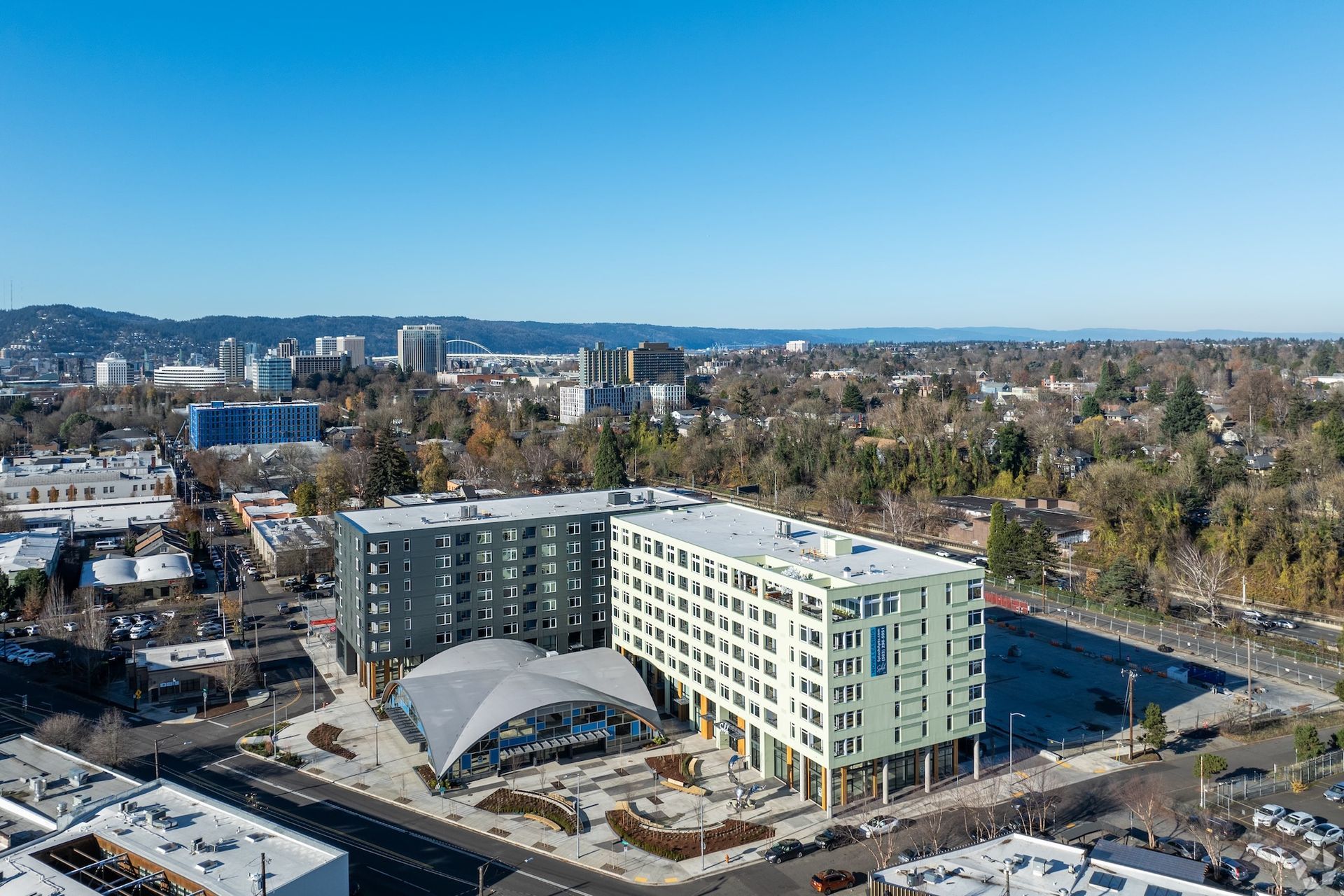 Aerial view of a modern apartment building with a curved entrance canopy in a city neighborhood