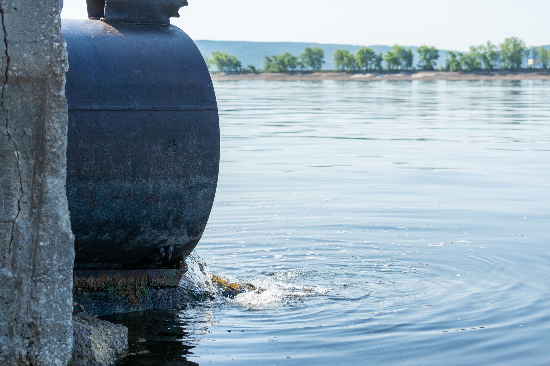 A large pipe is coming out of a body of water.