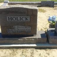 A red-brown granite headstone with the name 