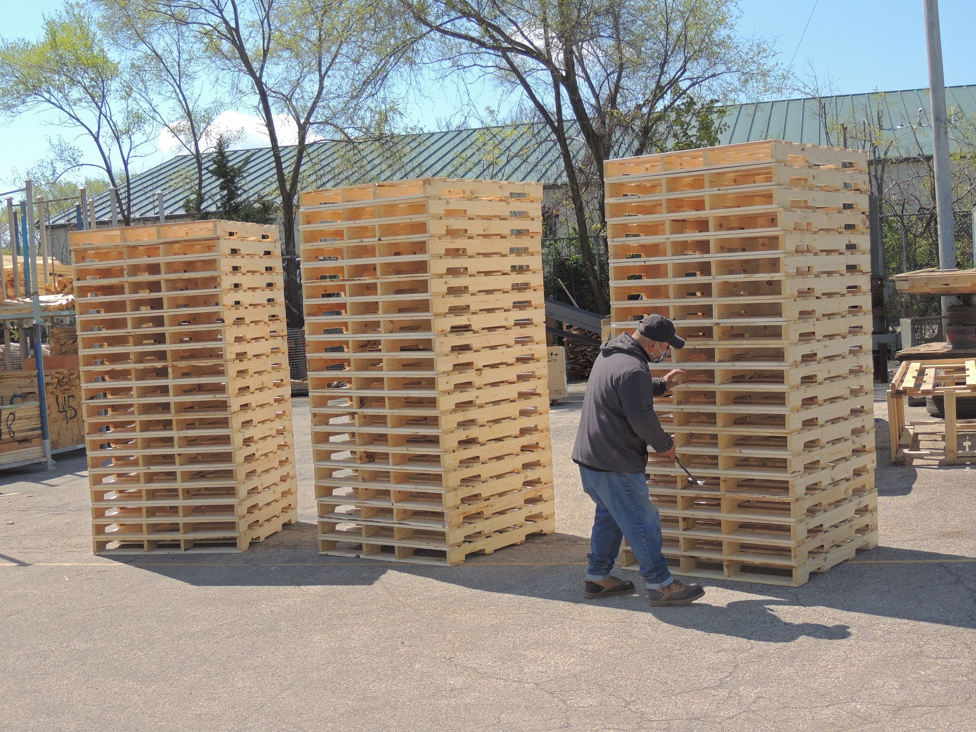 A man is standing in front of a stack of wooden pallets.
