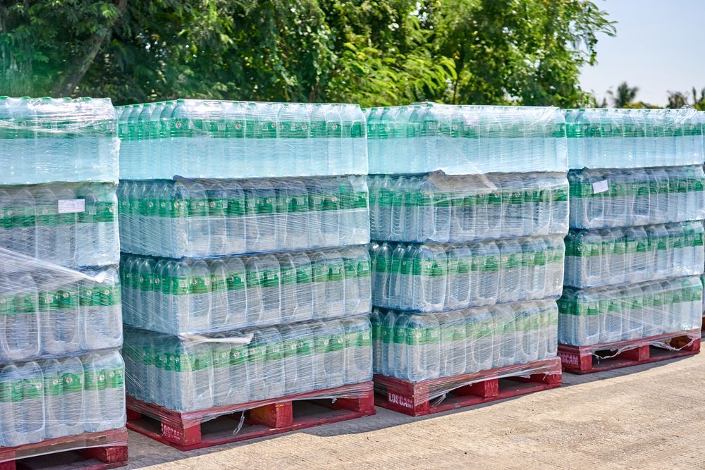 A row of plastic bottles stacked on top of each other on wooden pallets.