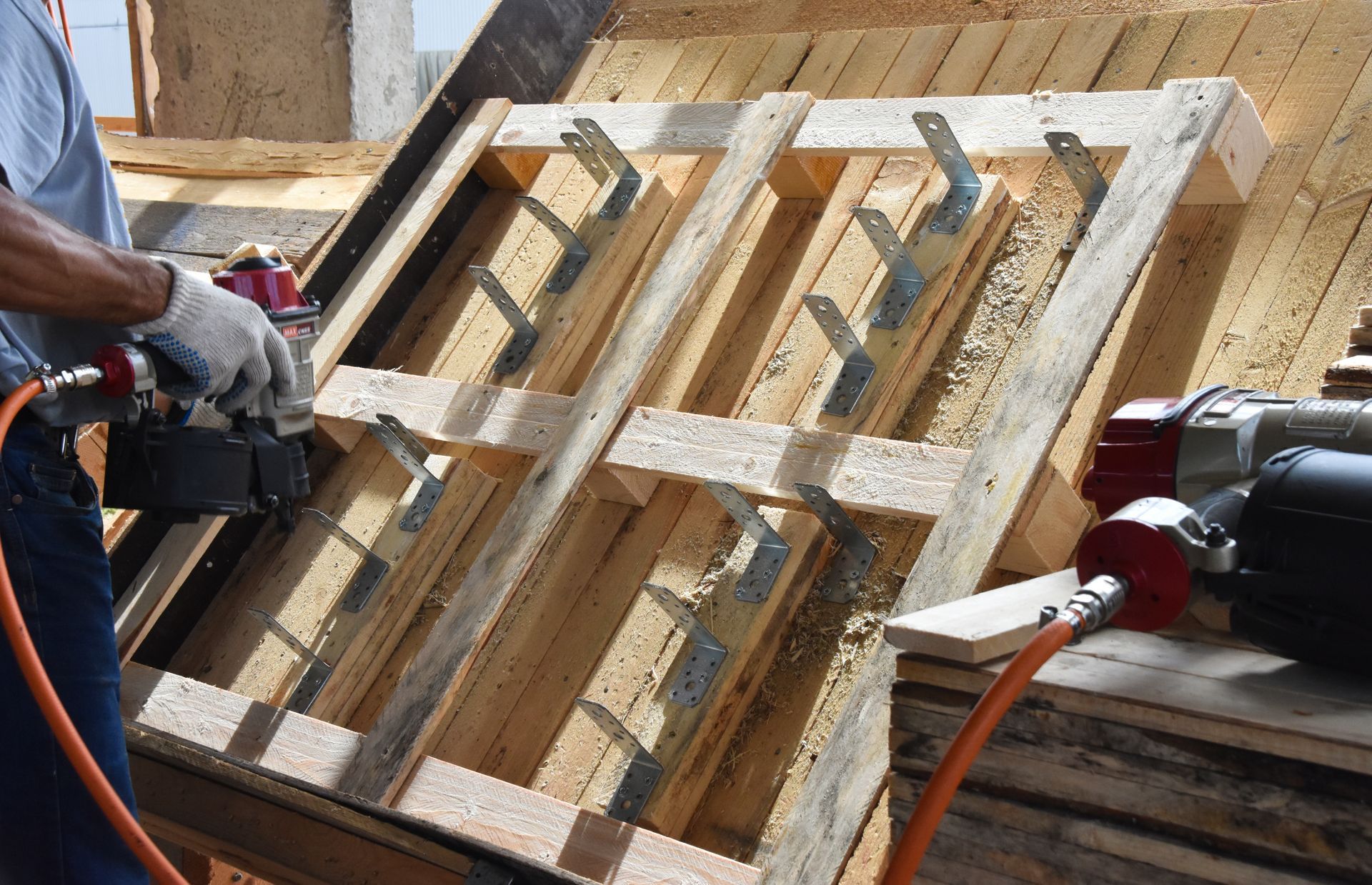 a man is working on a GMA wooden pallet with a tool