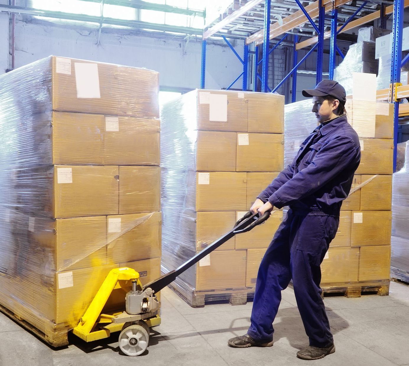 a man is pushing a yellow pallet truck in a warehouse with optimized pallets