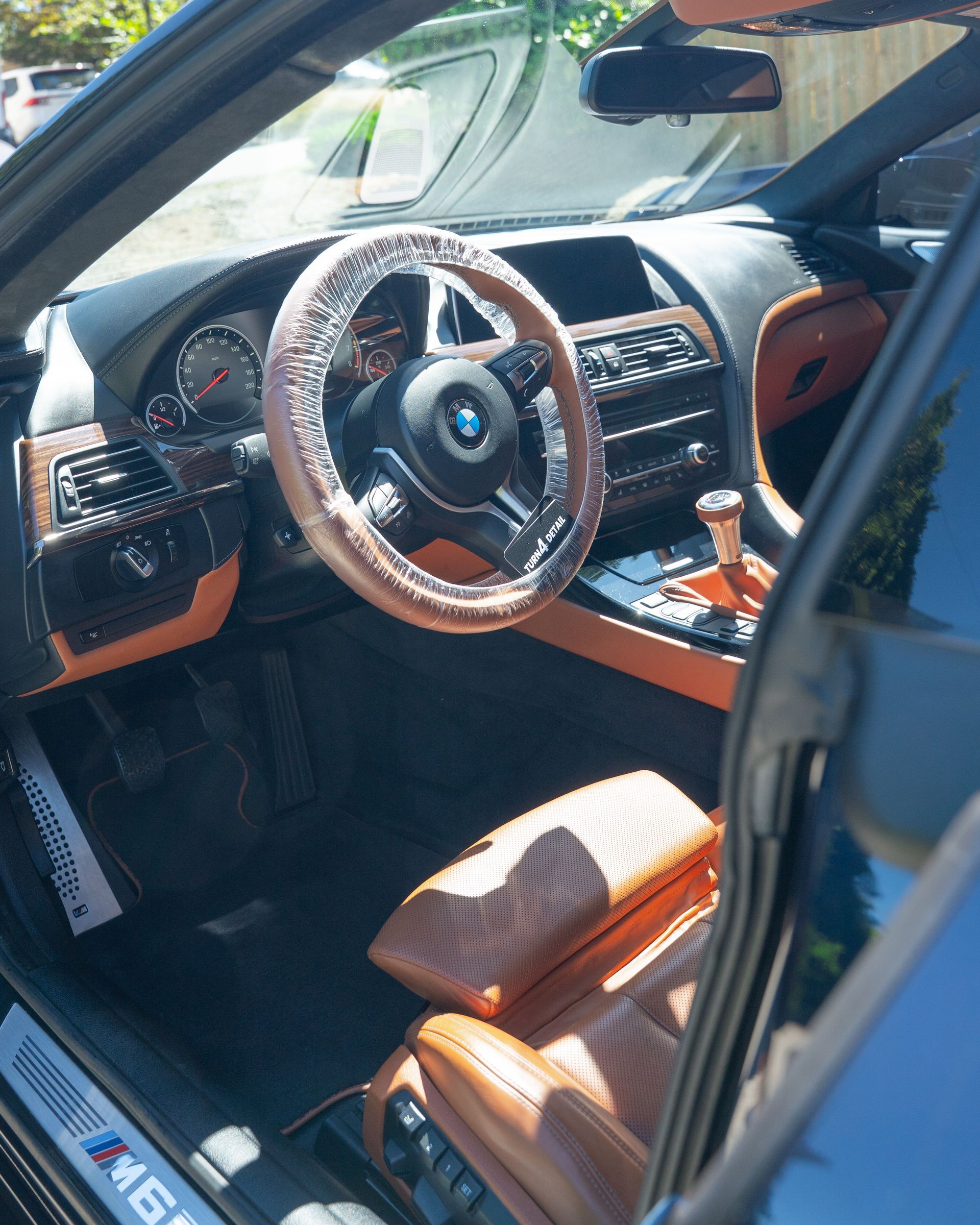 Luxury sports car interior with tan leather seats, wood trim, and a custom steering wheel.