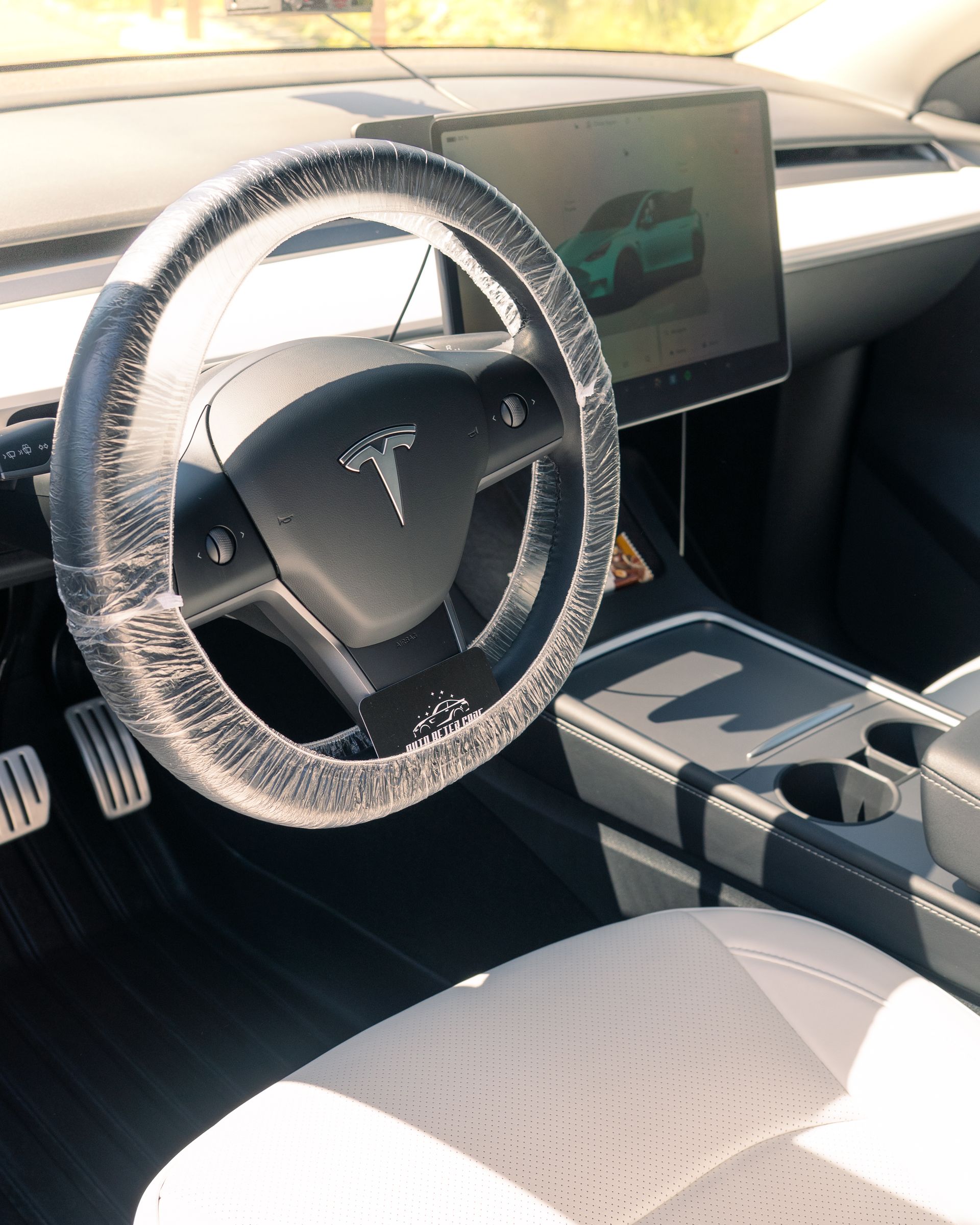 Tesla car interior with fuzzy steering wheel cover, center touchscreen, and white seats