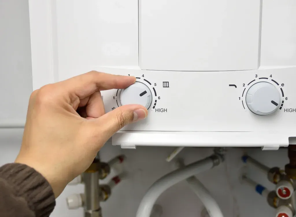 A person is adjusting the temperature of a water heater.