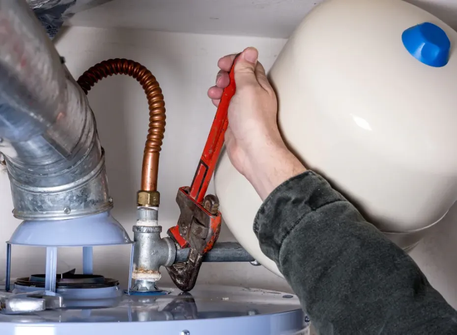 A person is fixing a water heater with a wrench