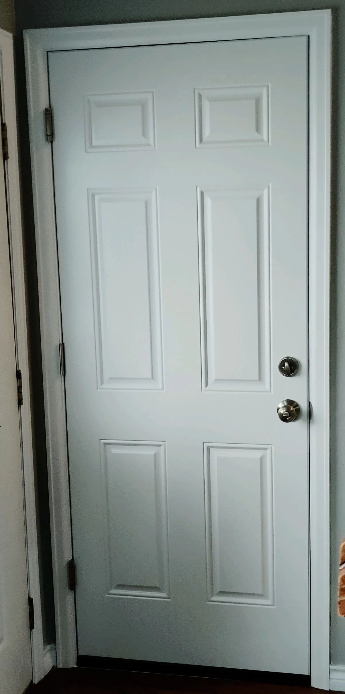 White paneled interior door with two round doorknobs and a dark wood floor