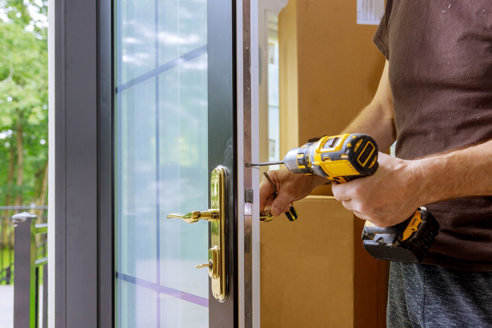 Person using a drill to install door hardware on a glass door.