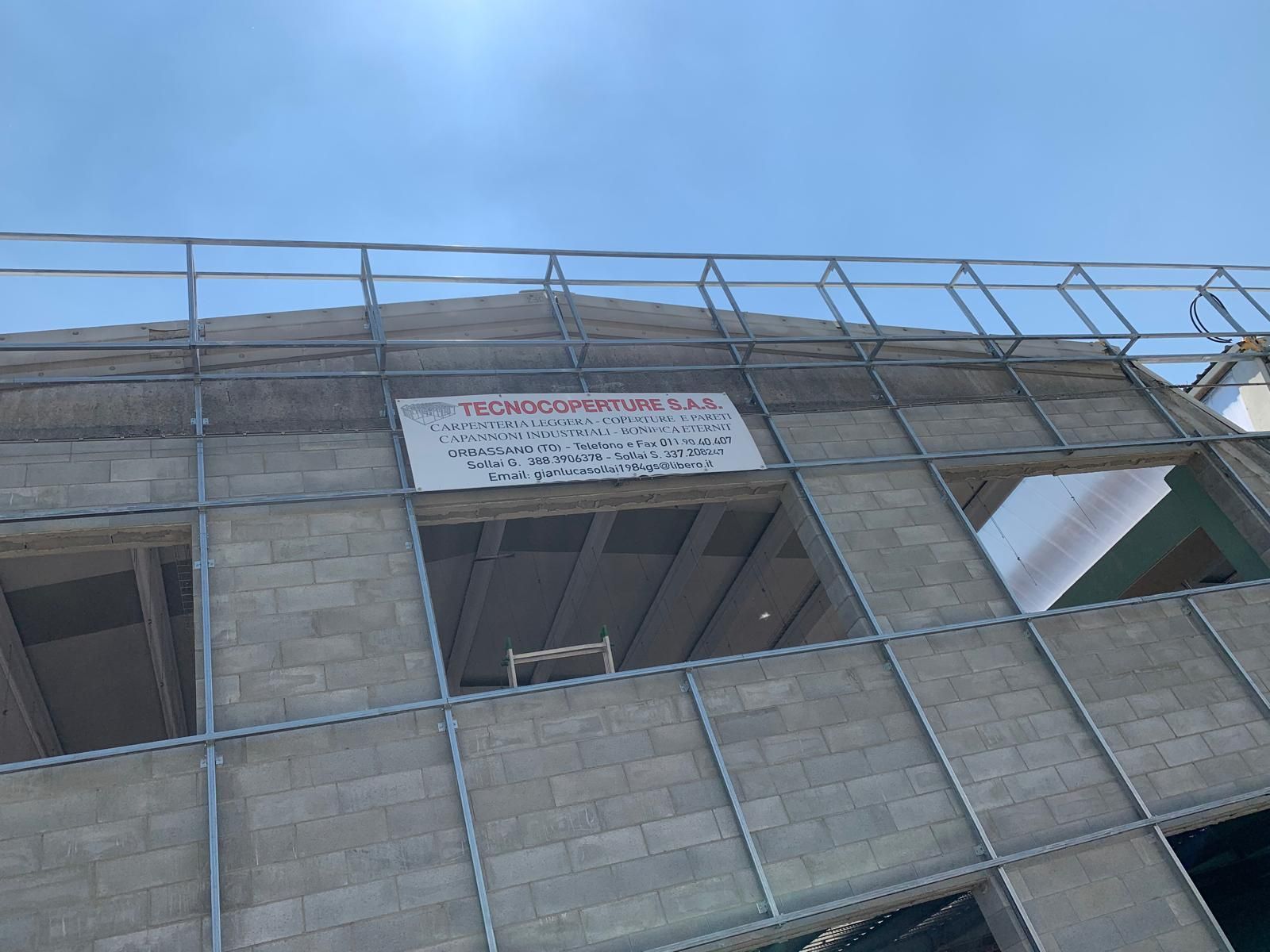 Impalcature attorno a un edificio in cemento con un cartello vicino al piano superiore