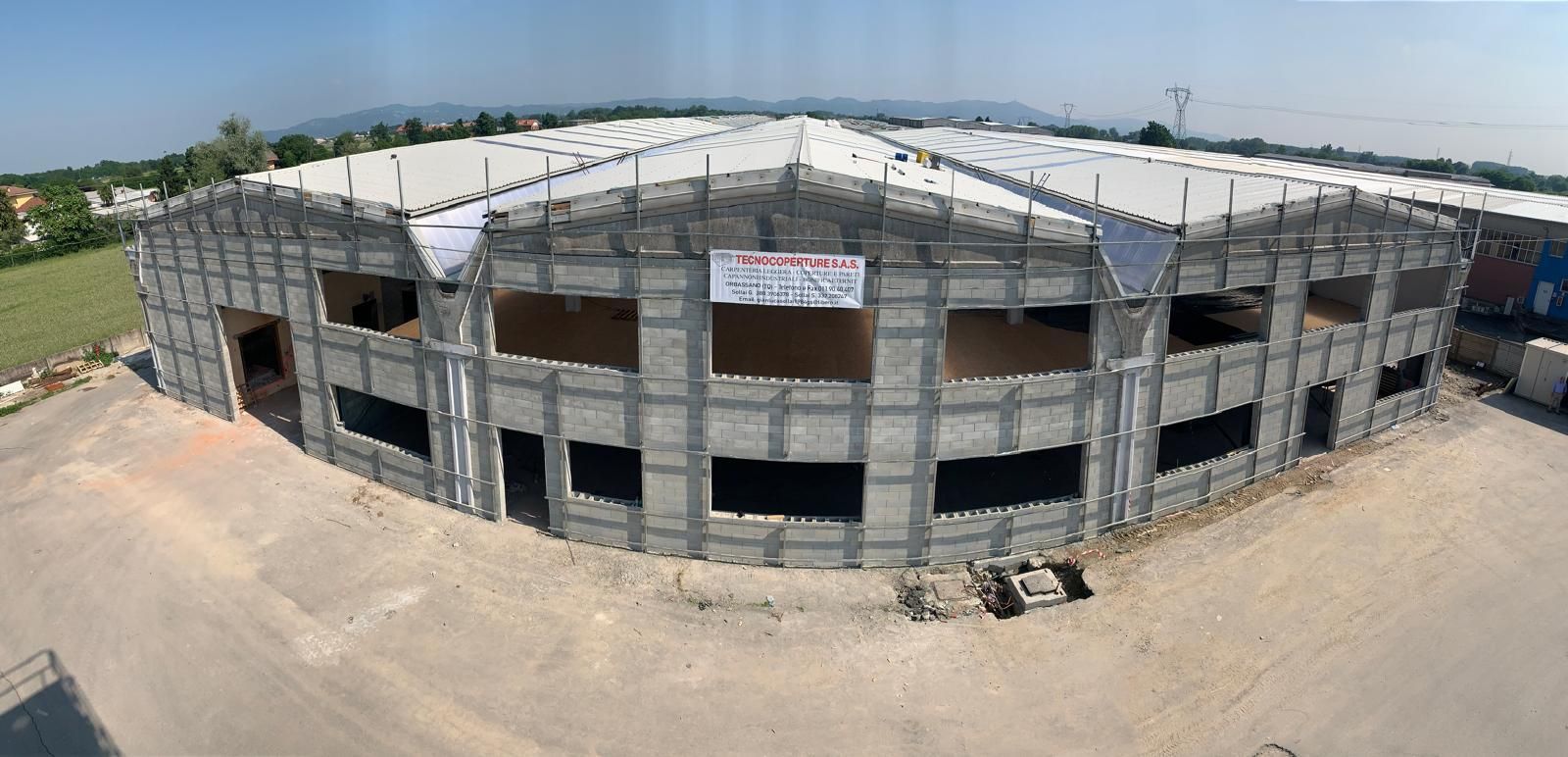 Veduta grandangolare di un edificio in cemento grezzo di colore grigio in costruzione, in una giornata di sole.