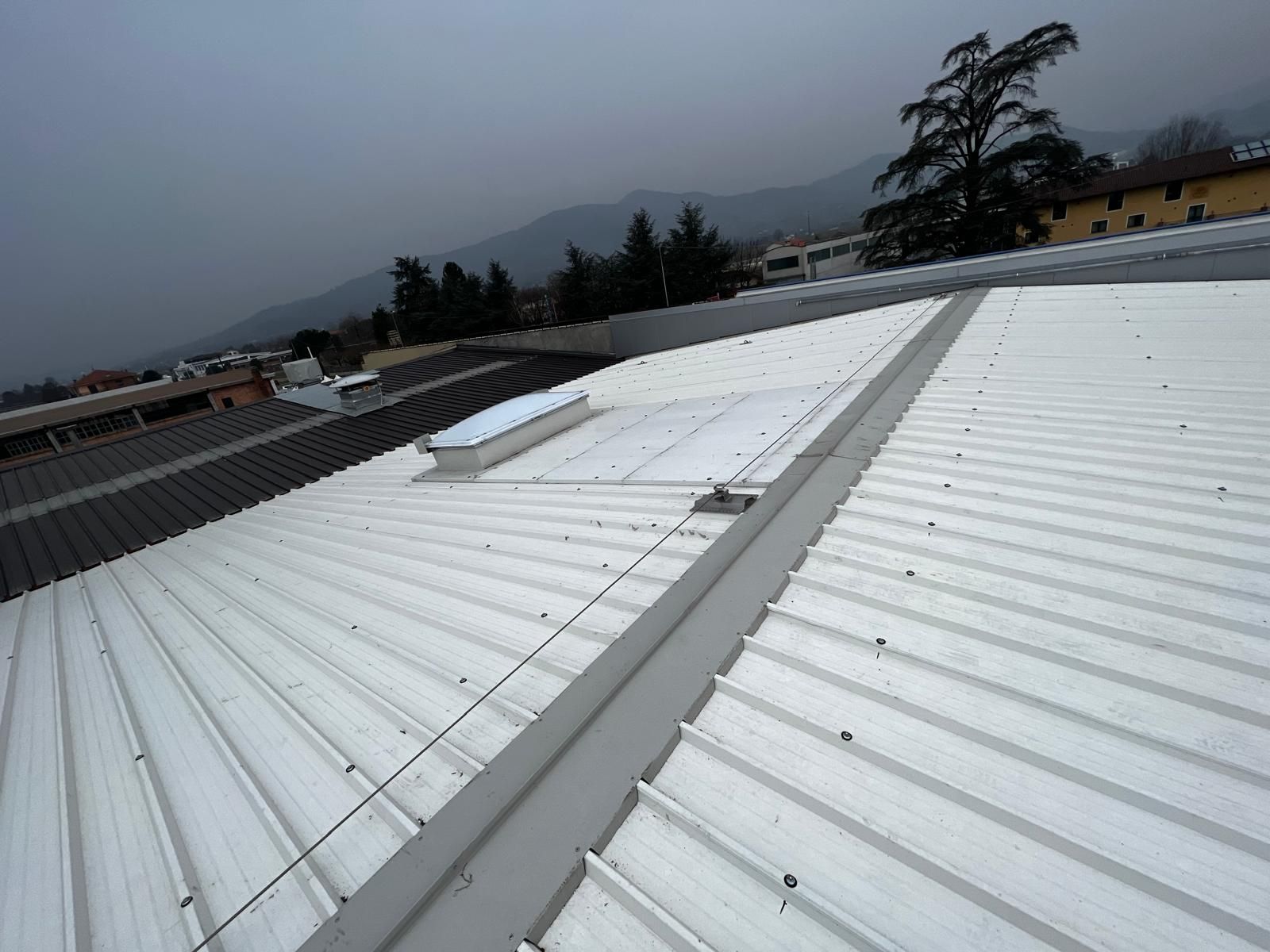 Tetto bianco ondulato con prese d'aria sullo sfondo di una montagna nuvolosa.