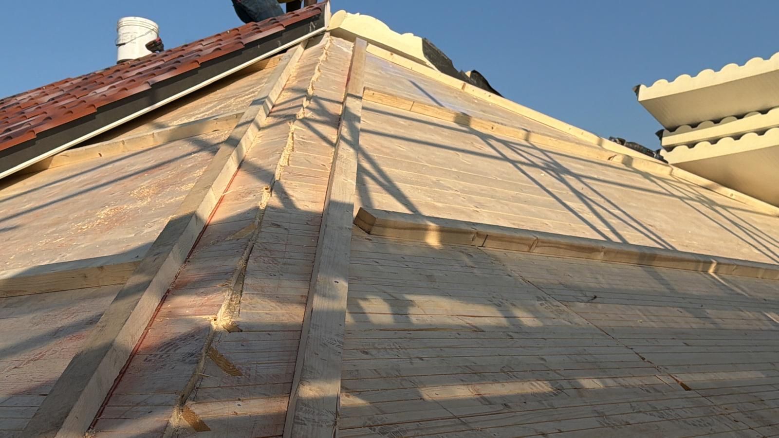 Tetto spiovente in costruzione con rivestimento in legno, tegole rosse e camino in mattoni al tramonto