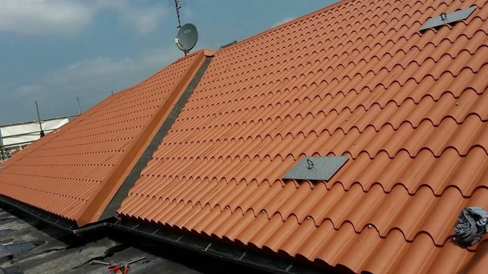 Tetto in tegole arancioni in costruzione con lucernari e parabola satellitare