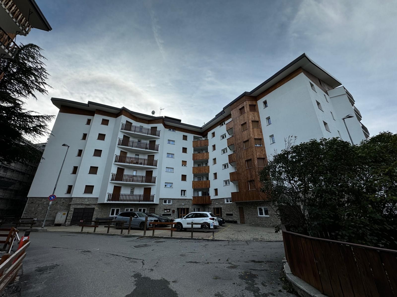 Palazzi e auto parcheggiate in un cortile residenziale al crepuscolo.
