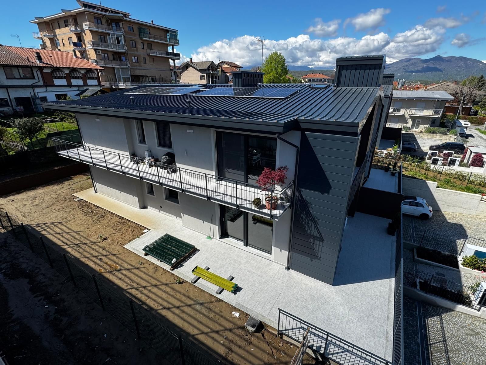 Una moderna casa a due piani con tetto grigio e pareti bianche, vista dall'alto in una giornata di sole.