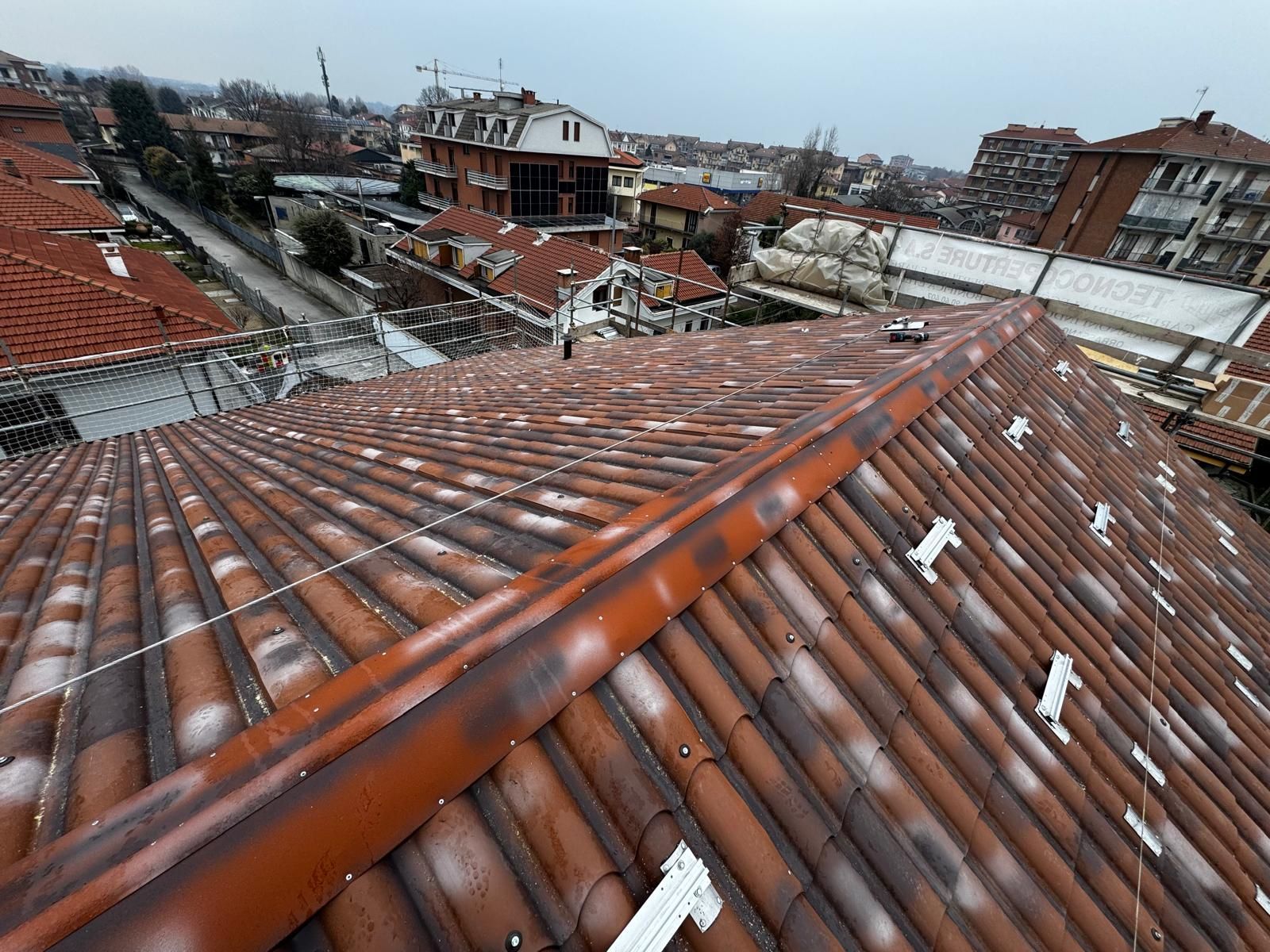 Tetti di tegole rosse imbiancati dalla neve in un quartiere degradato sotto un cielo nuvoloso