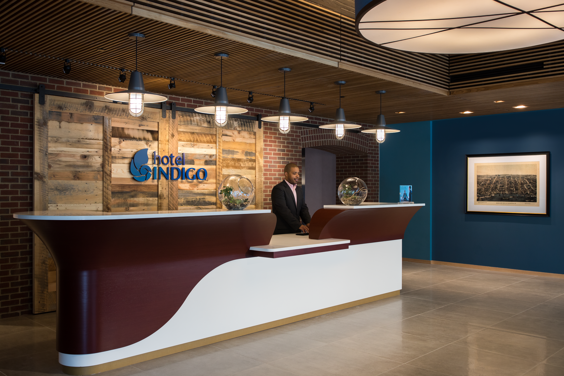 A man is standing at a reception desk in a hotel lobby.