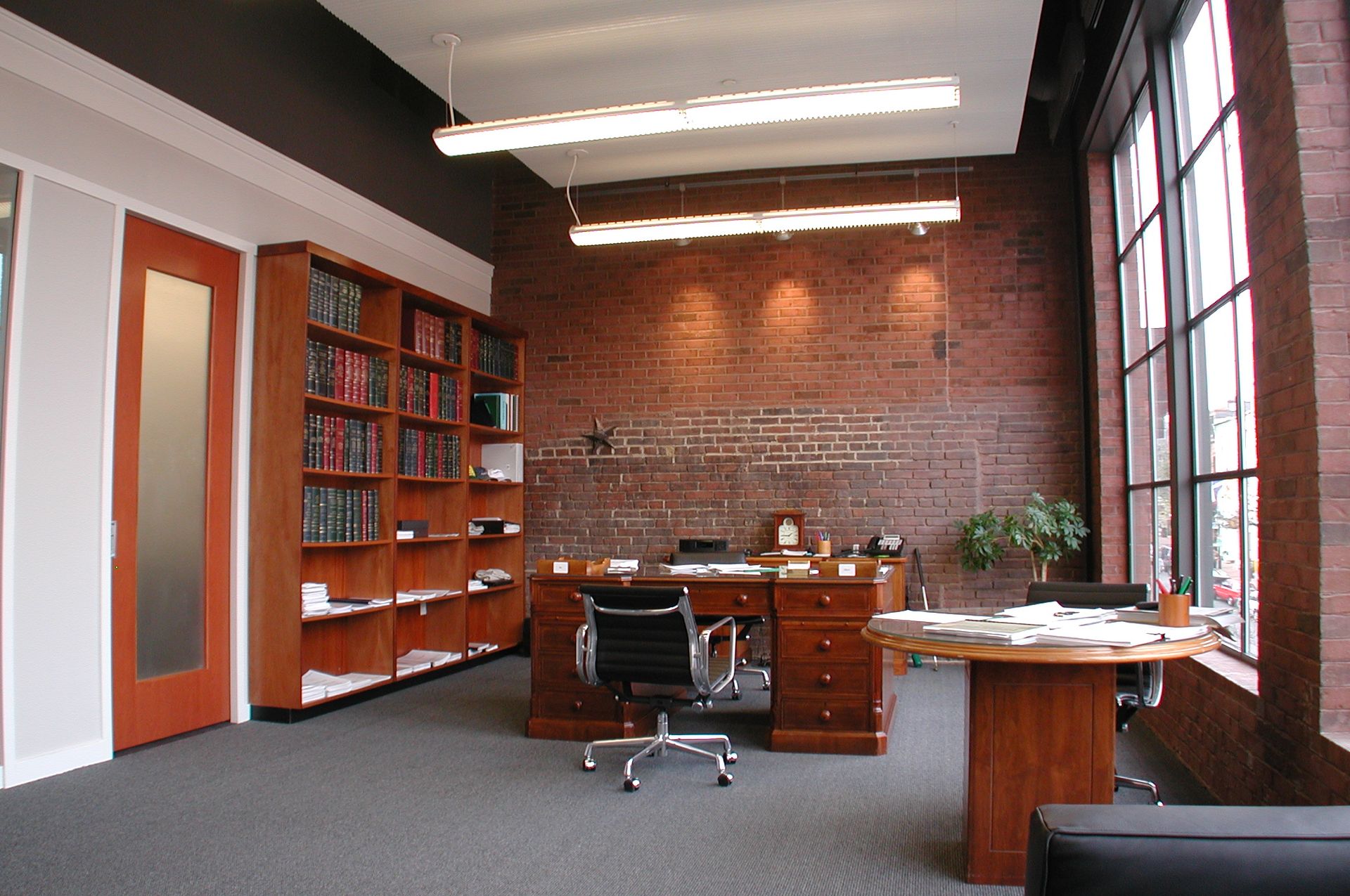 An office with a brick wall and a desk and chair