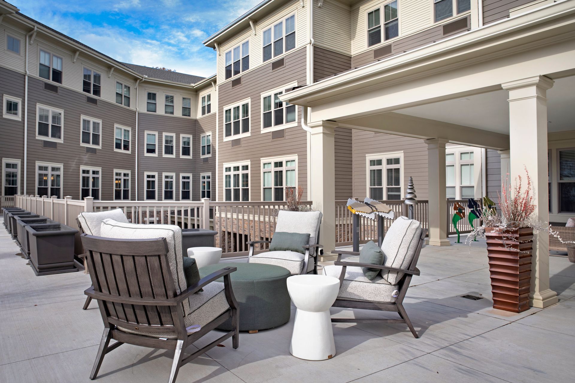 A large building with a patio area with chairs and tables in front of it.